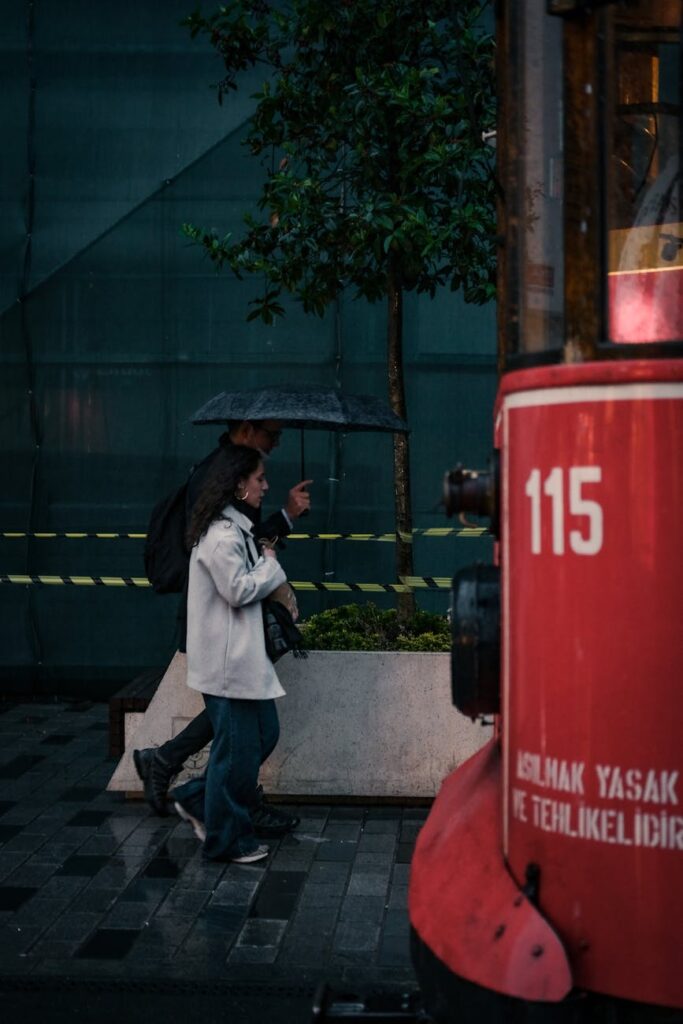 a man and woman walking on the sidewalk while raining